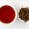 Cupped infusion of Dianhong Gongfu black tea and strained leaves.