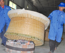 Two people lifting a large basket of Lu