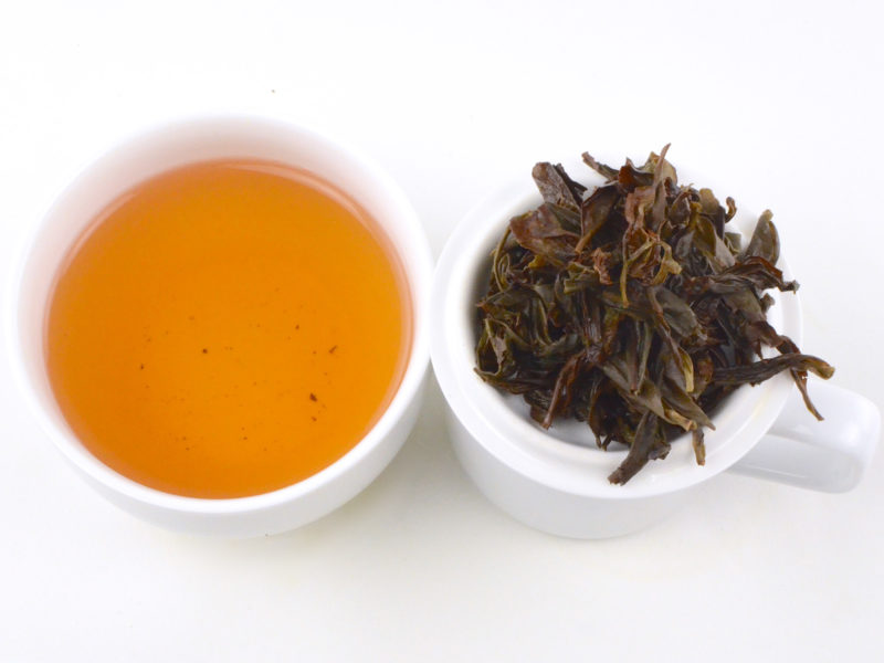 Cupped infusion of Ba Xian rock wulong tea and strained leaves.