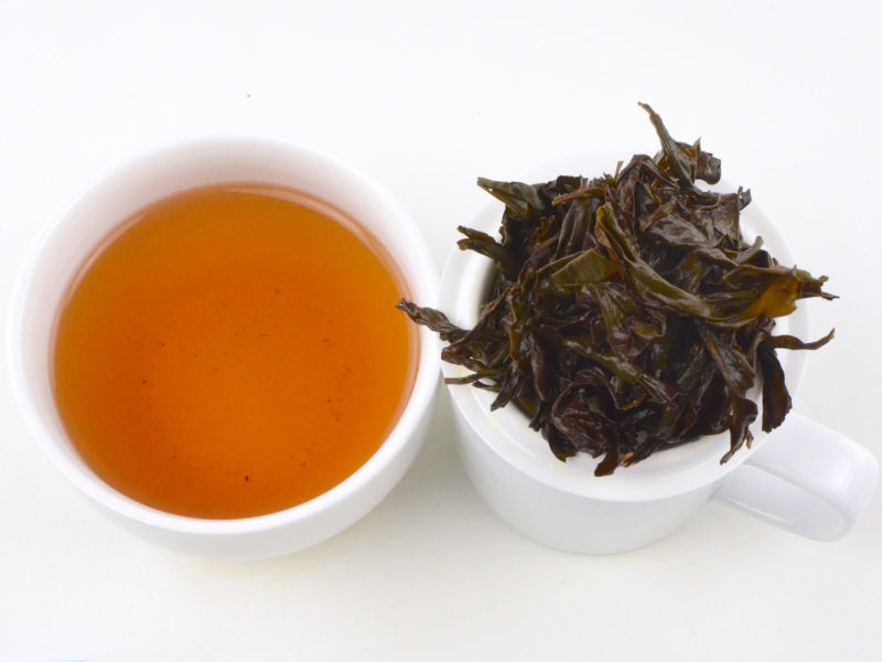 Cupped infusion of Qi Dan rock wulong tea and strained leaves.