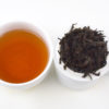 Cupped infusion of Rougui rock wulong tea and strained leaves.