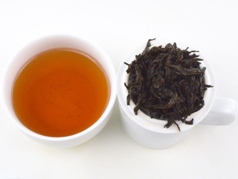 Cupped infusion of Rougui rock wulong tea and strained leaves.
