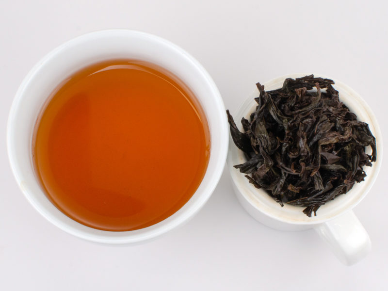Cupped infusion of Shui Jin Gui rock wulong tea and strained leaves.
