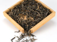 Daxueshan (Snow Mountain) sheng puer tea dry leaves in a wooden display box.