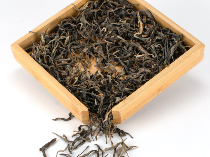 Daxueshan (Snow Mountain) sheng puer tea dry leaves in a wooden display box.