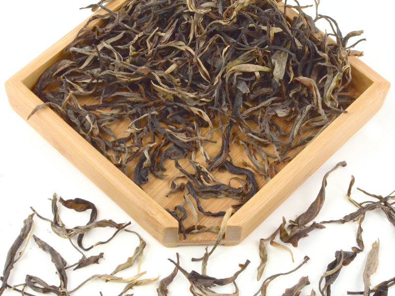 Daxueshan (Snow Mountain) sheng puer tea dry leaves in a wooden display box.