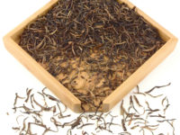 You Le Mountain sheng puer tea dry leaves in a wooden display box.