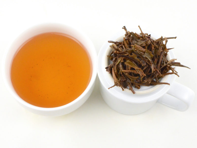 Cupped infusion of You Le Mountain sheng puer tea and strained leaves.