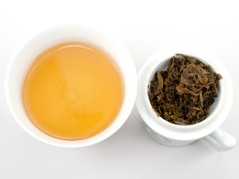 Cupped infusion of Jinggu Sheng Xiao Fangzhuan (Little Sheng Jinggu Brick) sheng puer tea and strained leaves.
