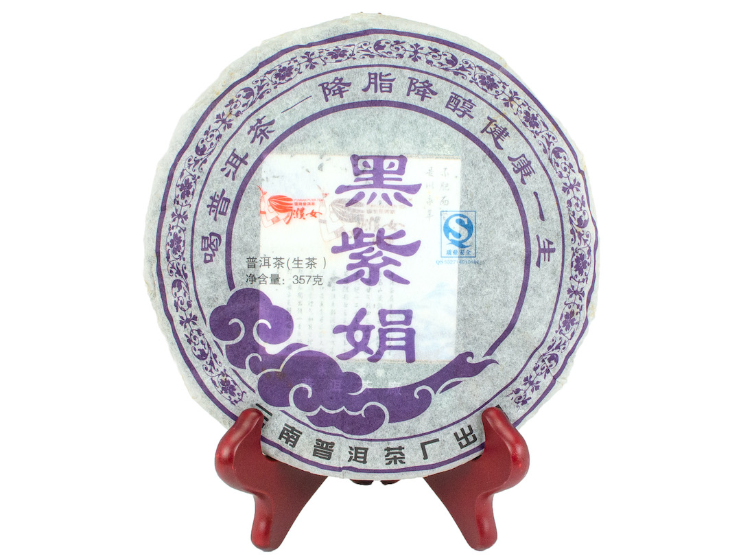 Hei Zijuan (Purple Leaf) sheng puer cake in paper wrapper.