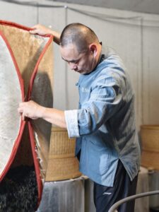 Tea maker, Mr. Zhou lifting a bamboo tray to mix the Wulong tea leaves every hour during 8-12 hour roasting sessions.