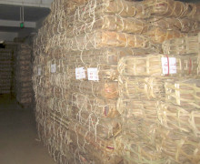 dozens of stacks of bamboo-wrapped puer cakes in a warehouse.