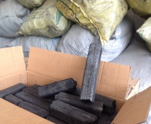 Bars of black charcoal in a box with bags of wulong mao cha behind.