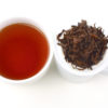 Cupped infusion of Lapsang Souchong black tea and strained leaves.