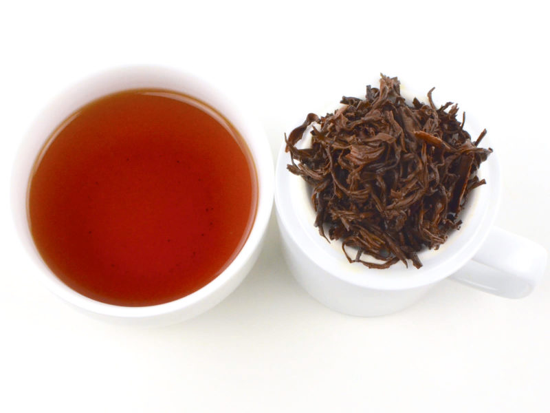 Cupped infusion of Lapsang Souchong black tea and strained leaves.