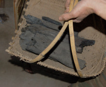 A basket of small black charcoal logs being carried.