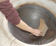 A hand reaching into a deep wok.