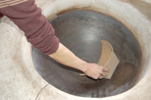 A hand reaching into a deep wok.