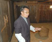 A man standing inside a room with smoke-darkened wooden walls.