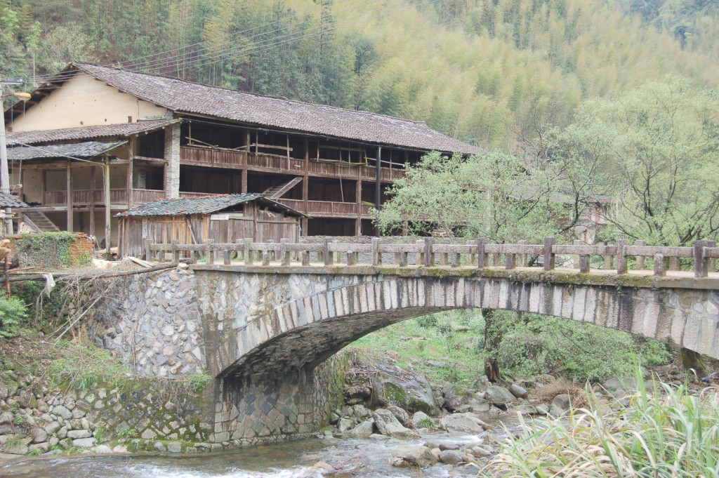 The oldest tea factory in Tongmu village. A wooden tea factory beside a river with a bridge.