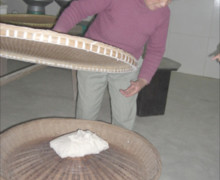 Placing the wrapped leaves in a bamboo tray over charcoal to continue oxidation.