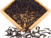 Xiao Hong Pao rock wulong tea dry leaves in a wooden display box.