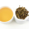 Cupped infusion of Moli Longzhu (Jasmine Pearls) scented green tea and strained leaves.