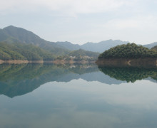 Tai Ping Lake and surrounding green hills, reflected in the water.