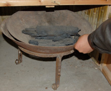 A low bowl of black charcoal being slid under an oven.