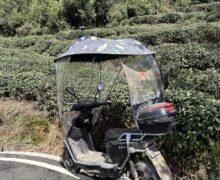 Mengding Ganlu tea gardens in the background with a tea pickers electric bike. It rains a lot in Yaan City, Sichuan Province, China so the bikes have rain coverings