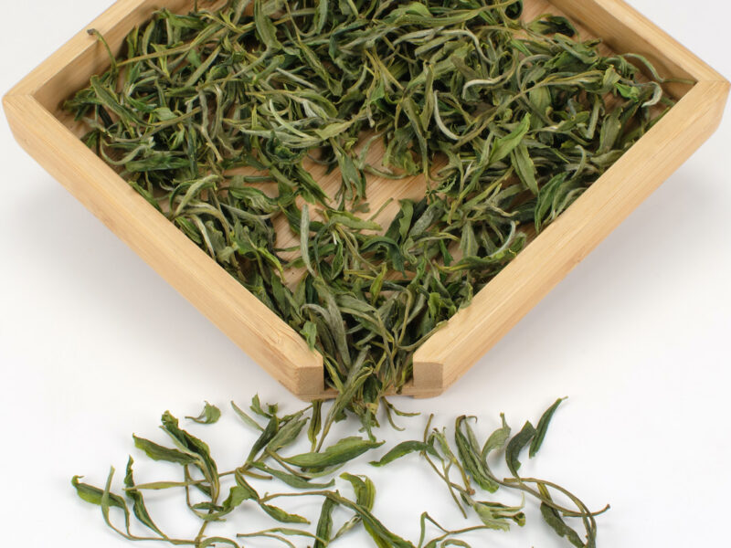 Huangshan Maofeng green tea dry leaves in a wooden display box.