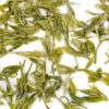 Huangshan Maofeng green tea leaves floating in clear water.