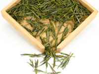 Guzhu Zisun (Purple Bamboo Shoot) tea leaves displayed on a bamboo tray.