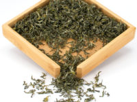 Mengding Ganlu (Sweet Dew) green tea dry leaves in a wooden display box.