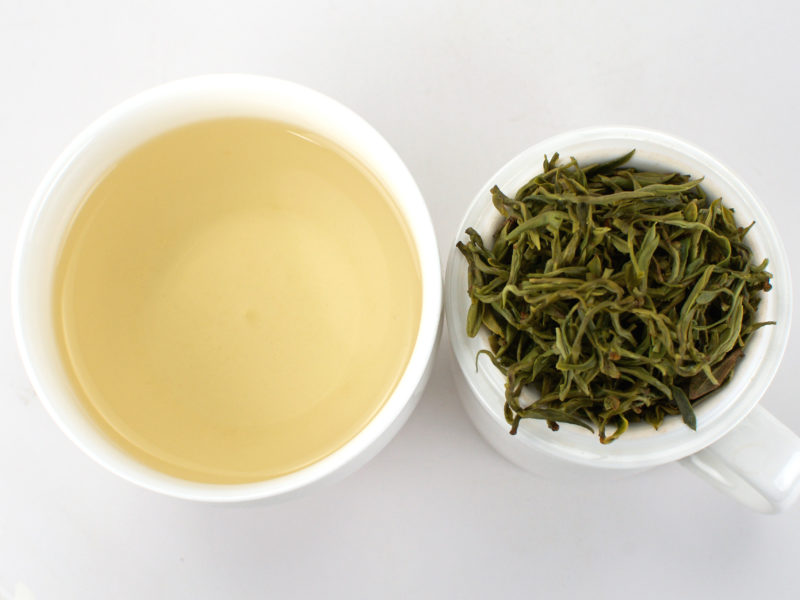 Cupped infusion of Mengding Ganlu (Sweet Dew) green tea and strained leaves.