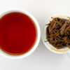 Cupped infusion of Jinya (Yunnan Golden Buds) black tea and strained leaves.