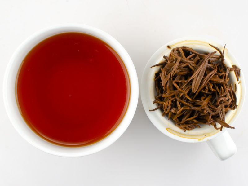 Cupped infusion of Jinya (Yunnan Golden Buds) black tea and strained leaves.