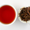Cupped infusion of Jin Konque (Golden Peacock) black tea and strained leaves.