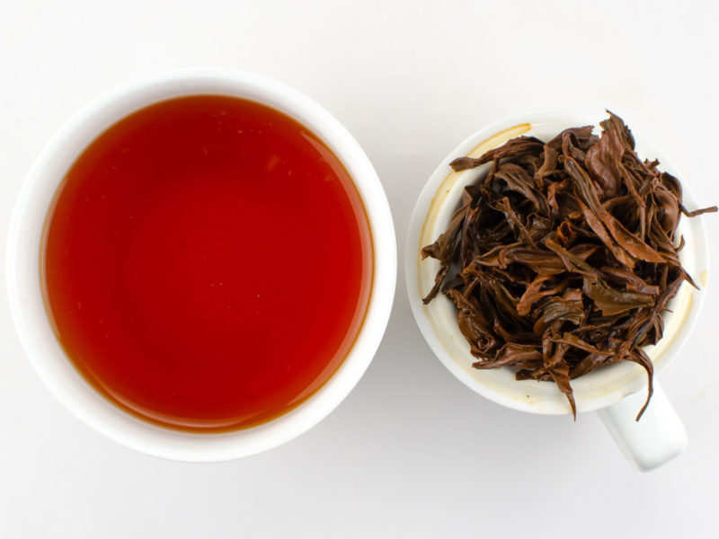 Cupped infusion of Jin Konque (Golden Peacock) black tea and strained leaves.