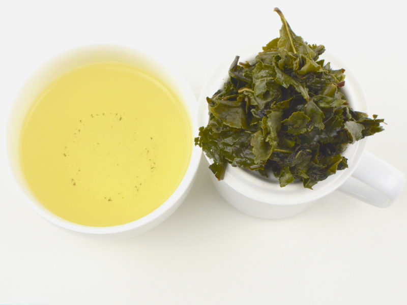 Cupped infusion of Jin Guanyin Anxi wulong tea and strained leaves.