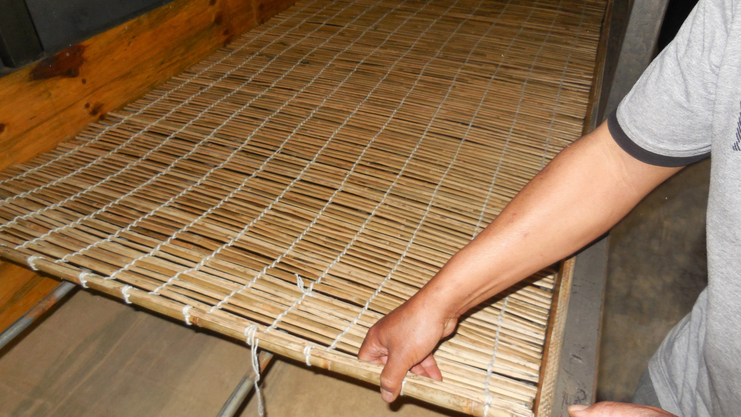 Laying a woven bamboo mat across bars in the upper part of the trough so that there is still space underneath it.