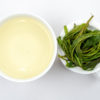 Cupped infusion of Tai Ping Hou Kui green tea and strained leaves.