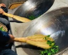 two woks frying Sunflower Seed Chinese green tea with brooms made from local plants