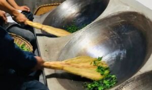 two woks frying Sunflower Seed Chinese green tea with brooms made from local plants