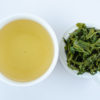 Cupped infusion of Yun Wu green tea and strained leaves.