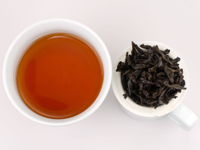 Cupped infusion of Tie Luo Han rock wulong tea and strained leaves.