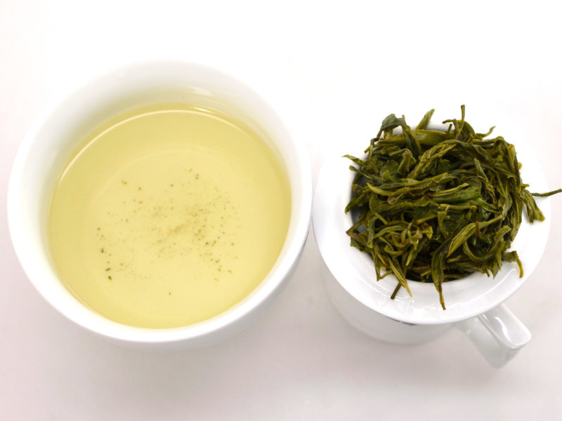 Cupped infusion of Maojian green tea and strained leaves.