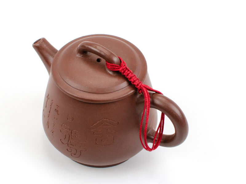 A braided red cord connecting a yixing teapot's lid to its handle.
