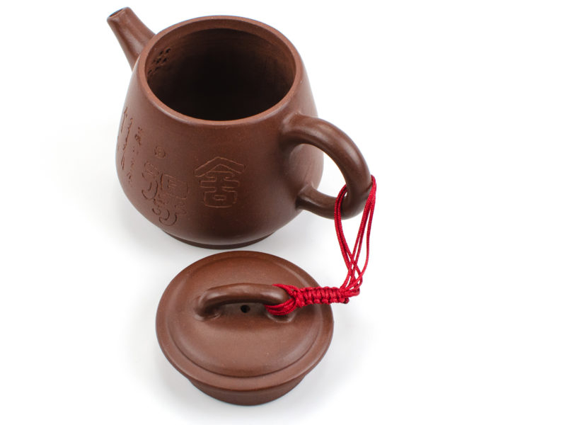 A braided red cord connecting a yixing teapot's lid to its handle even when open.