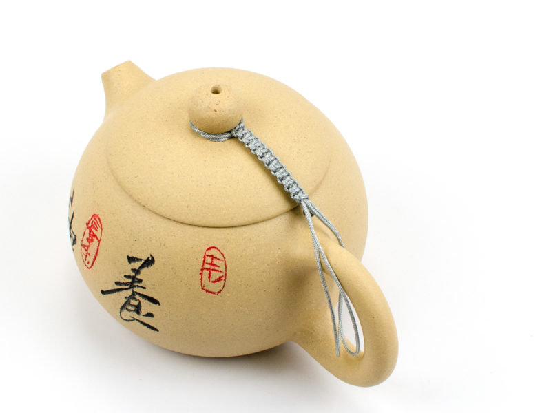 A braided silver cord connecting a yixing teapot's lid to its handle.